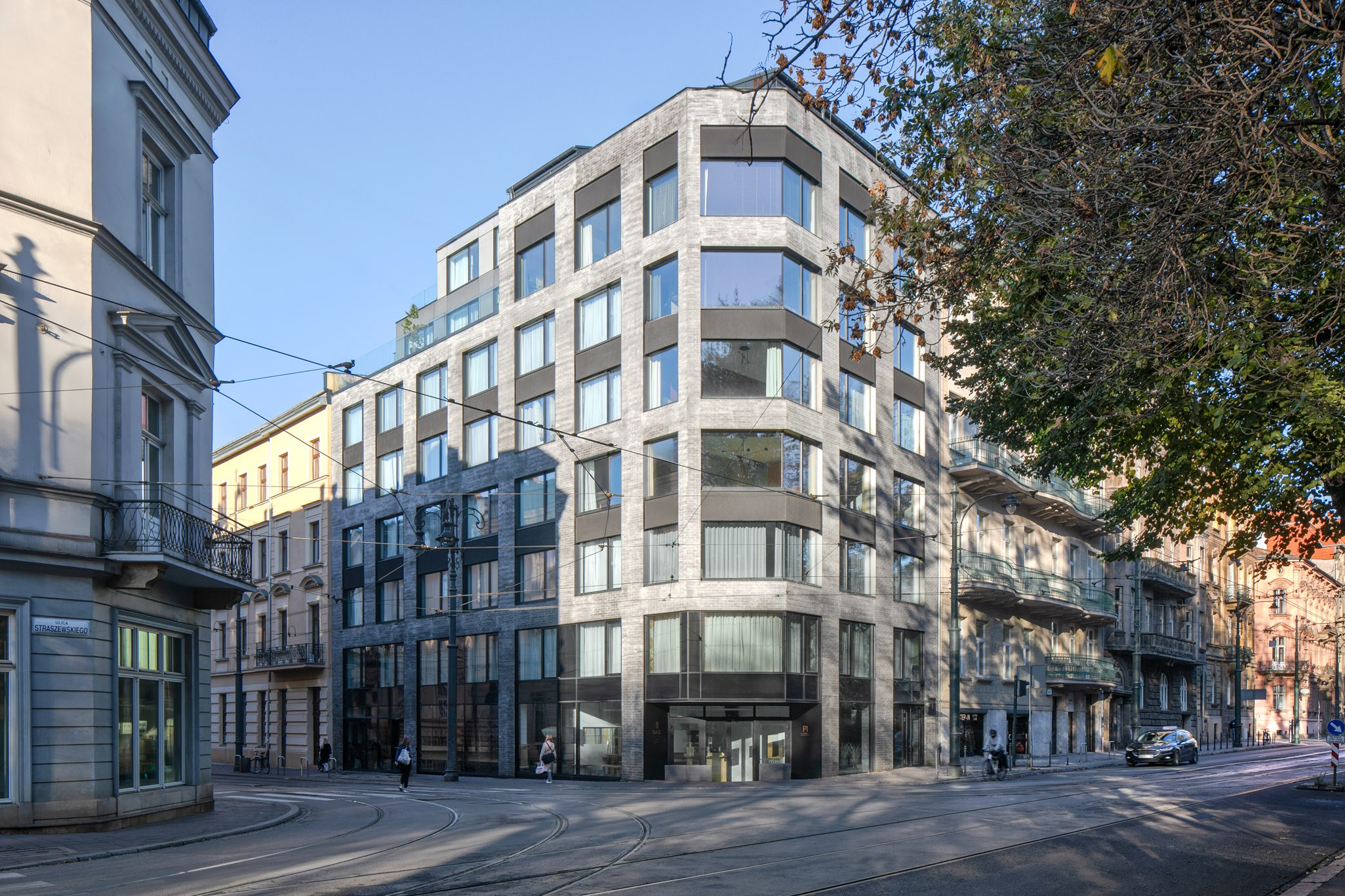 Großes Bürogebäude mit vielen Fenstern, umgeben von Straßeninfrastruktur, Fahrzeugen, Fußgängern, Bäumen und einem bewölkten Himmel, das als neuer Firmensitz dient.
