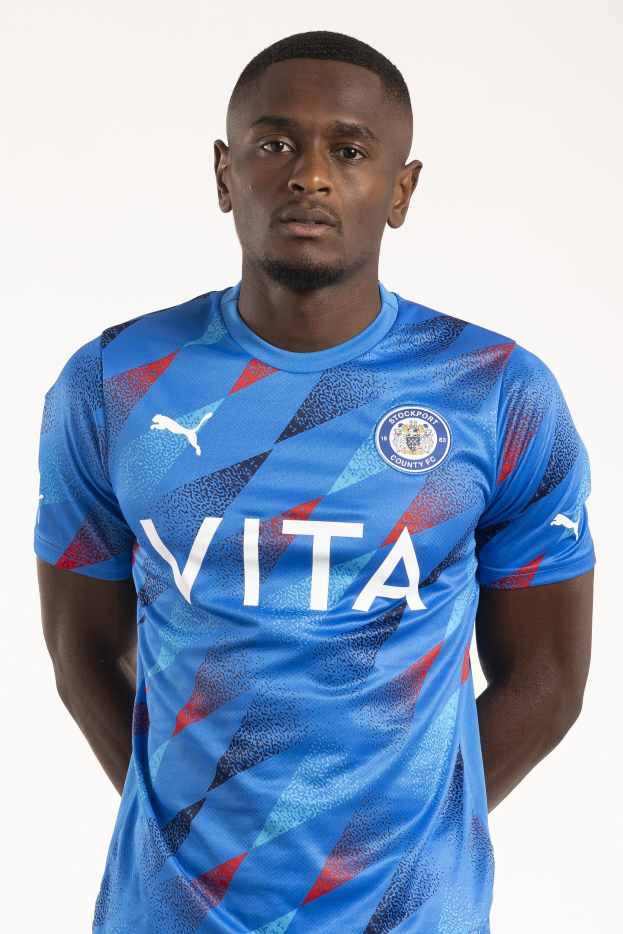 Ein Mann in einem blauen Auswärtsshirt von Leicester City aus der Saison 2018-19, der mit den Händen in den Taschen und einem leichten Lächeln dasteht.