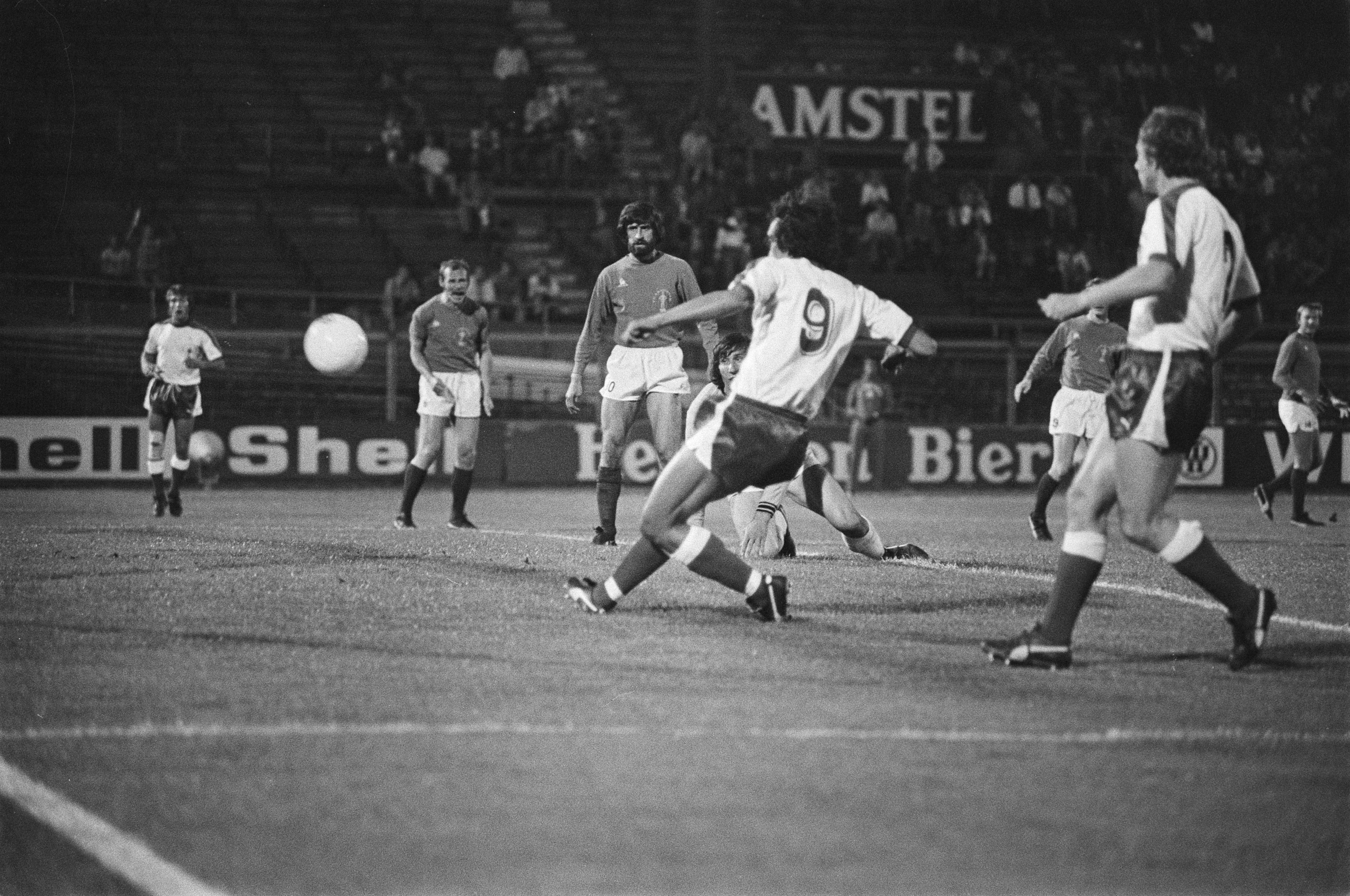 Schwarzes und weißes Bild von Männern, die Fußball in einem Stadion spielen, mit Zuschauern im Hintergrund.