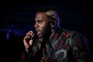 DJ Khaled trägt eine schwarze und rote Jacke und singt in ein Mikrofon auf der Bühne beim Coachella Valley Music and Arts Festival 2018 in Indio, Kalifornien mit einem dunklen Hintergrund.