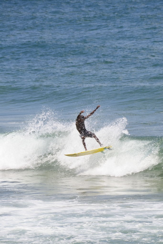 Ein Mann steht auf einem Surfbrett und reitet eine Welle im Wasser.