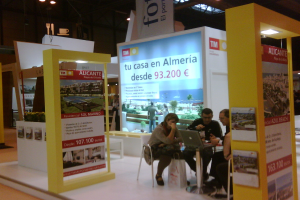 Eine Gruppe von Menschen sitzt um einen Tisch herum und schaut auf einen Laptop, mit mehreren Flyern, auf denen verschiedene Werbeanzeigen zu sehen sind.