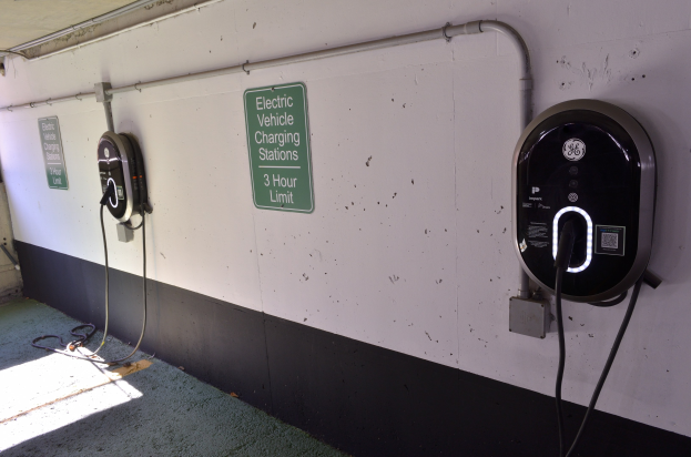 Elektrofahrzeug-Ladestationen an einer Wand in einer Tiefgarage montiert, mit Informationsschildern in der Nähe und dem Boden darunter sichtbar.