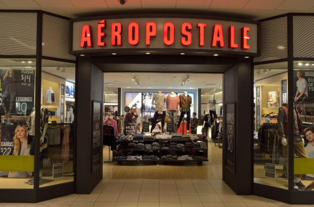 Aeropostale-Laden im Einkaufszentrum mit Schaufensterpuppen in Kleidern, Kleiderständern, Informationsschildern, Glaswänden und Beleuchtung, mit Hinweisschildern auf die Schließung im Juni.