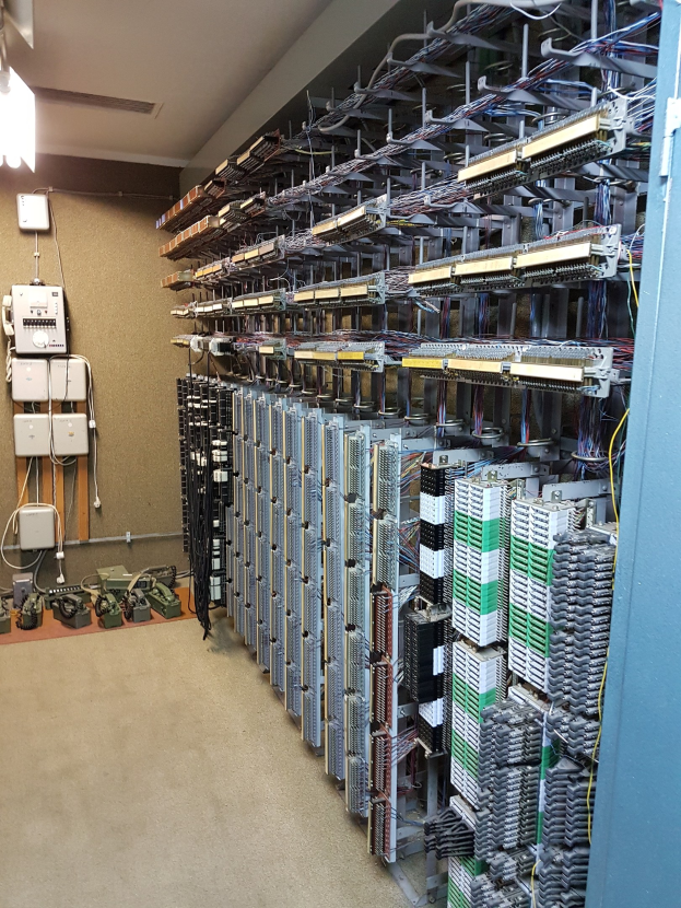 Großer Raum voller Server, Kabel und elektronischen Geräten, typisch für ein Rechenzentrum.