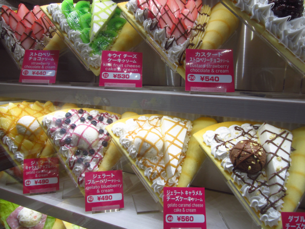 Vitrine mit verschiedenen Eissorten in bunten Farben und Formen, jede mit einem Preisschild.