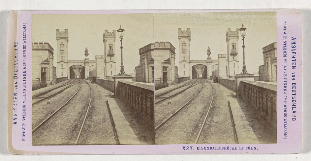 Schwarz-weißes stereoskopisches Bild einer Eisenbahnbrücke in Köln, Deutschland, das die Eisenbahninfrastruktur und die umliegenden Elemente zeigt.