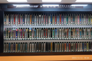 Eine hell erleuchtete Bibliothek mit hohen Bücherregalen voller Bücher, mit einer Texttafel und einem Wasserzeichen unten, ähnlich einer Selbstbedienungsbibliothek in Stadtblöcken.