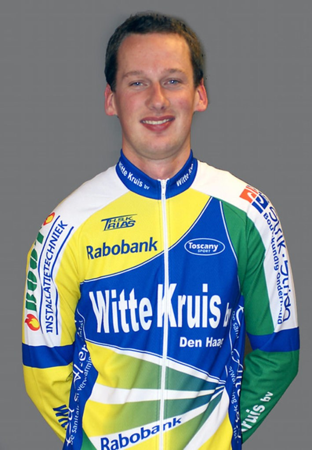 Ein männlicher Athlet posiert für ein Foto mit sichtbaren Sponsorenlogos auf seinem Hemd.