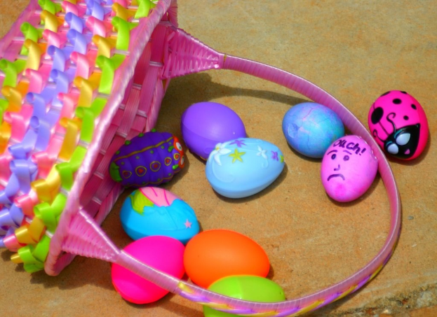 Ein geflochtener Korb mit mehreren farbenfrohen Ostereiern auf einer Wand.