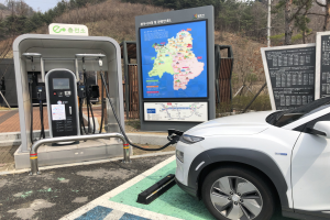 Ein Elektroauto, das an einer Ladestation in Seoul, Südkorea, lädt, umgeben von Bäumen mit dem Himmel im Hintergrund.