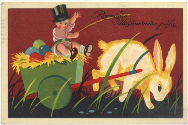 Alte Postkarte mit einem Baby in einem Zylinder, das einen Karren mit bunten Ostereiern schiebt, begleitet von einem Kaninchen, mit handgeschriebener Ostergrüß.
