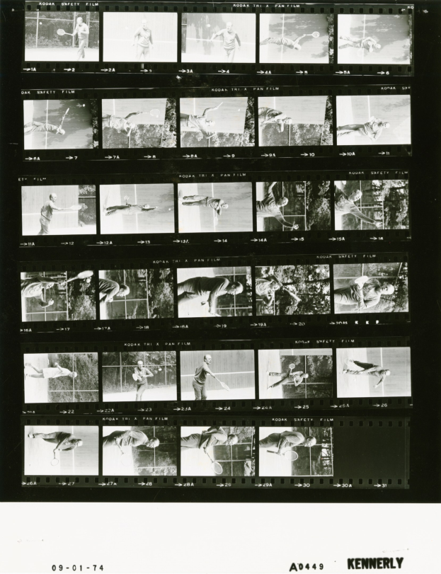 Schwarzes und weißes Foto eines konzentrierten Mannes in einem weißen Hemd und Shorts, der Tennis spielt und einen Schläger hält, mit einem Filmstreifen im Hintergrund.