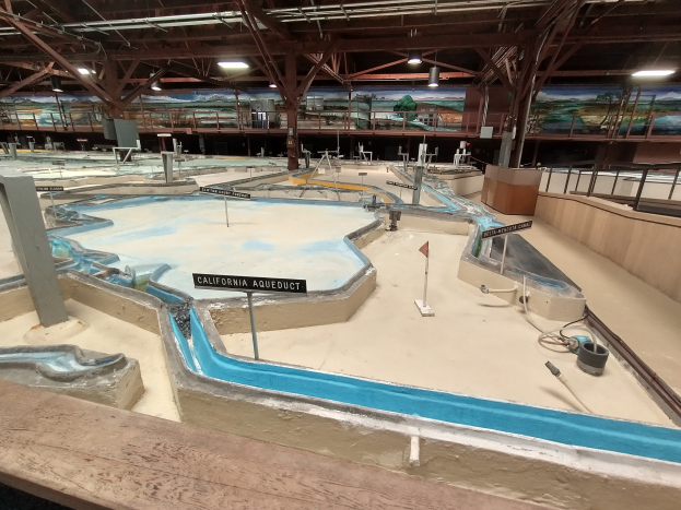 Indoor-Wasserpark mit mehreren Rutschen, Stangen, beleuchteter Decke, Wandgemälden und einem Minigolfplatz.