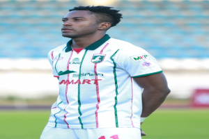 Der ghanaische Fußballspieler Emmanuel Adebayor steht auf einem Fußballfeld und trägt ein weißes und grünes T-Shirt und Shorts.