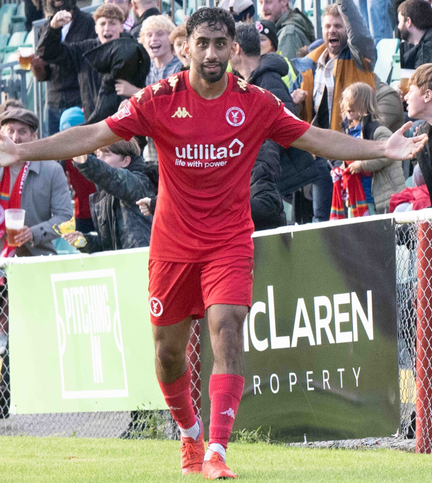 Ein Fußballer in roter Uniform rennt mit ausgebreiteten Armen auf einem Feld, im Hintergrund ist eine Zuschauermenge zu sehen und ein Banner mit der Aufschrift "Middlesbrough FC v Swansea City - Sky Bet Championship" im Vordergrund.