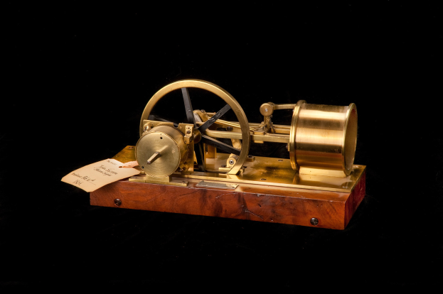 Altmodische Uhr mit einem Holzunterbau, Metallrad und angebrachten Papier-Zeitschalter auf einem schwarzen Hintergrund.