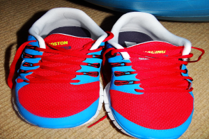 Ein Paar rote und blaue Schuhe mit Text darauf, vor einem unbestimmten Objekt positioniert.