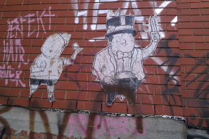 Eine Ziegelwand mit verschiedenen Postern und Graffiti.