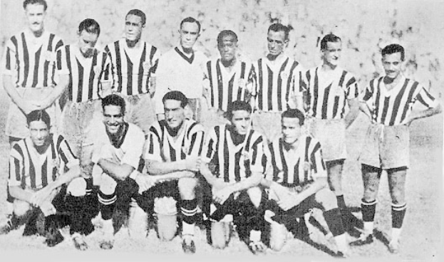 Ein Schwarz-Weiß-Foto einer Fußballmannschaft, bei der einige Spieler stehen und andere auf dem Boden sitzen, und Text unten.