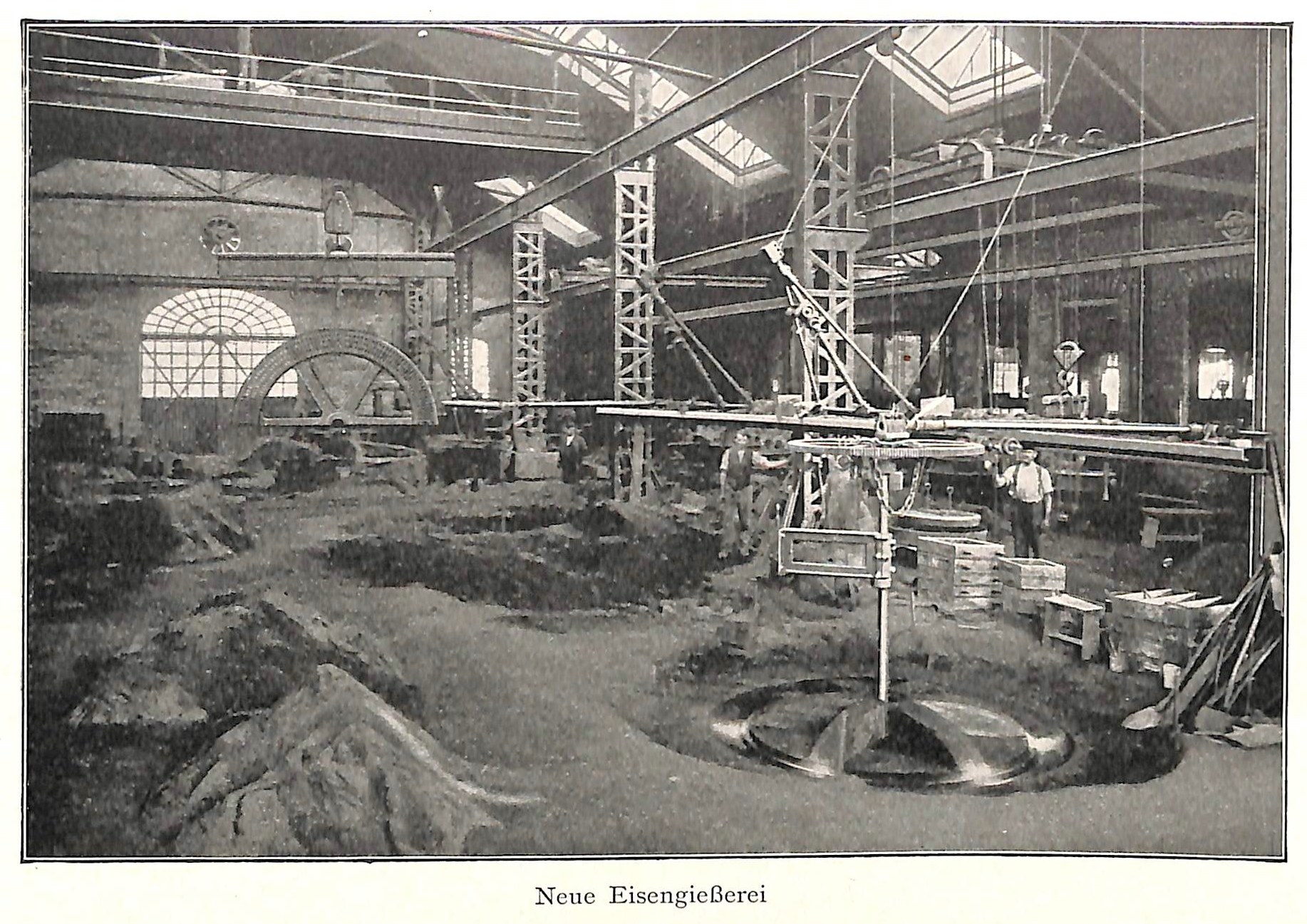 Schwarzes und weißes Foto einer frühen deutschen Fabrik mit Arbeitern, die an einer Maschine arbeiten, umgeben von Metallstangen und -pfählen, beschriftet mit 'Neue Eisenglebeerei, die erste Fabrik in Deutschland' unten.