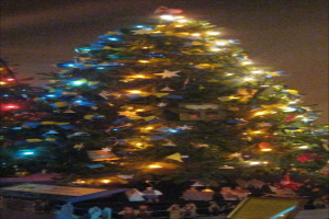 Ein geschmückter Weihnachtsbaum mit Statuen von Menschen darunter auf einem Tisch.