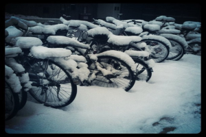 Mehrere Fahrräder stehen auf einem schneebedeckten Boden, der ebenfalls mit Schnee bedeckt ist.