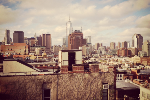 Luftaufnahme einer Stadt mit zahlreichen Geb├Ąuden und einem bew├Âlktem Himmel.