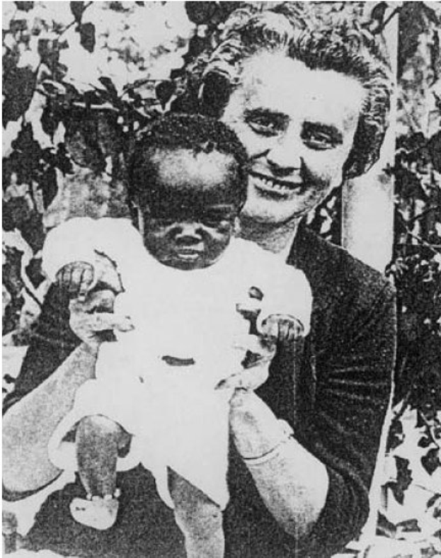 Ein Schwarz-Weiß-Foto einer Frau, die strahlend ihr Baby hält, mit Blättern im Hintergrund