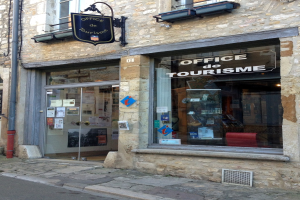 Touristeninformationsgebäude mit "Office de Tourisme"-Schilder, Fenstern, Tür mit Papieren, Seitenrohr und Straße unten.