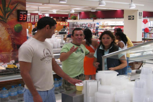 Eine Gruppe von Menschen in einem Einkaufsladen mit Lebensmitteln auf Regalen und Lampen an der Decke.