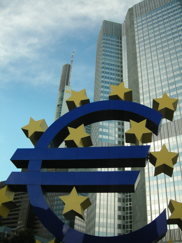 Euro-Zeichen vor dem Hauptquartier der Europäischen Zentralbank in Frankfurt, Deutschland, mit Bäumen und bewölktem Himmel.