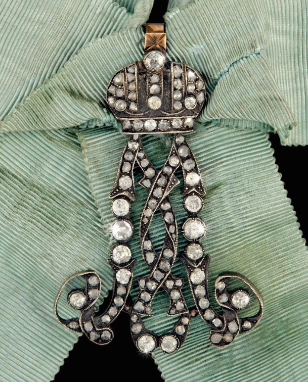 Gold- und Diamantanhänger mit einer Krone auf einem grünen Tuchhintergrund.