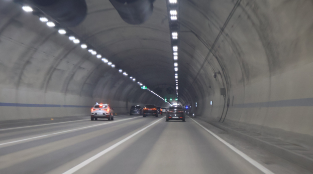 Ein Auto fährt durch einen Tunnel mit Deckenleuchten, beleuchtet von der Beleuchtung.