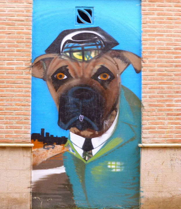 Ein Wandgemälde eines detailreichen, farbenfrohen Hundes in Anzug und Krawatte auf der Seite eines Gebäudes.