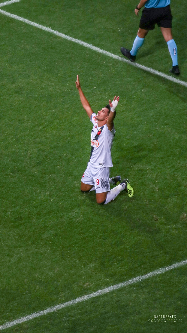 Ein Fußballer in Uniform kniet auf dem Boden und streckt die Arme aus, um zu feiern.