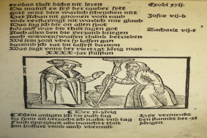 Ein Papier mit gedrucktem Text in einer fremden Sprache, mit zwei Männern im Hintergrund, möglicherweise aus einem Lehrbuch.