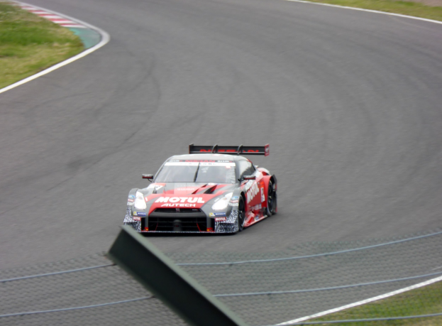 Ein Nissan GT-R Nismo GT3 Rennauto auf der Nürburgring 24 Stunden Rennstrecke, umgeben von grünem Gras auf beiden Seiten.